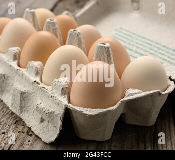 Fresh whole brown eggs in paper packaging on a gray wooden background Stock Photo