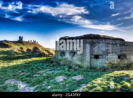 Dunstanburgh Castle and a World War Two bunker on a hill above Embleton, Northumberland Stock Photo