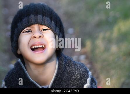 Close up portrait of a little boy crying in the park, selective focus Stock Photo