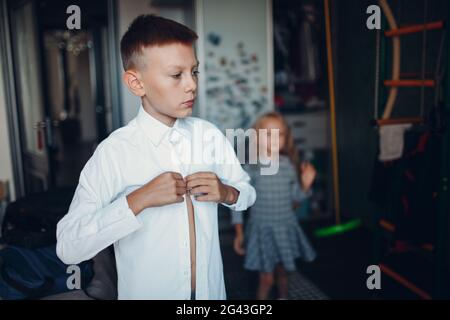Young boy and his little sister dressing uniform preparation back to school. Stock Photo