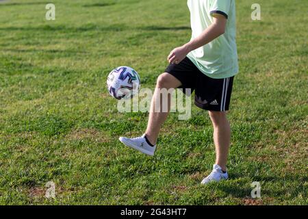 Football freestyle. Young man practices with soccer ball. Player training the basic tricks with the ball. Stock Photo