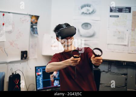 Young man gamer in virtual reality goggles, VR glasses headset with joystick Stock Photo