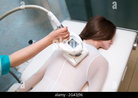 Young beautiful woman and LPG massage procedure in spa clinic. Lymphatic drainage massage LPG apparatus process. Stock Photo