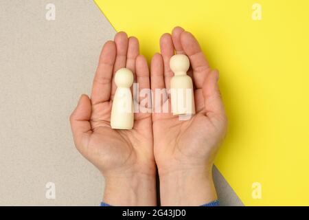 Female hand holds wooden figurines of men in the palm Stock Photo