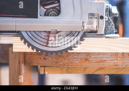Sawing wood in the garage: Home handyman sawing plank of wood with circular saw Stock Photo
