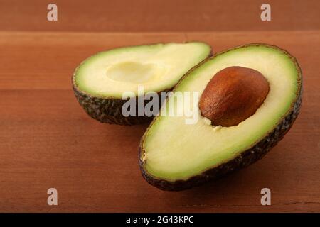 Closeup Avocado cut in half on wooden board background Stock Photo