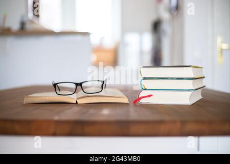 Knowledge and science concept: Stack of books and glasses lying on wooden desk, home. Stock Photo