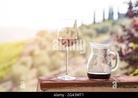 Glass of red wine at Tuscany. Wine yards in the background. Sunshine. Stock Photo