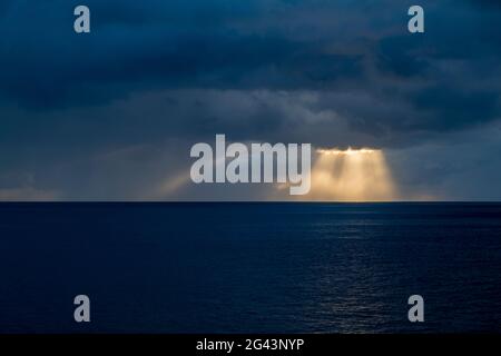 Sun rays break through storm clouds near Fatu Hiva, Marquesas Islands, French Polynesia, South Pacific Stock Photo