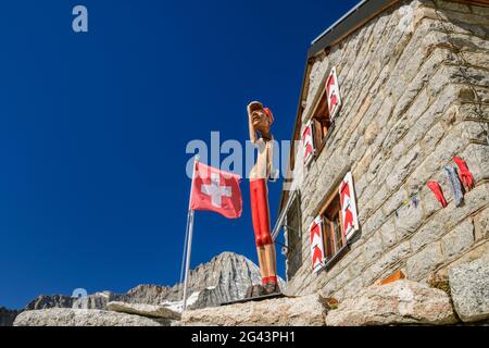 Hut Baltschiederklause with Swiss flag and wooden figure, Baltschiederklause, Bernese Alps, Valais, Switzerland Stock Photo