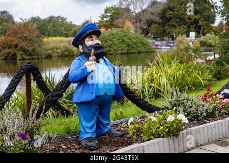 Figure in the garden, sailor, pipe, flowerbed, Greetsieler Sieltief, canal, Greetsiel, East Frisia, Lower Saxony, Germany Stock Photo