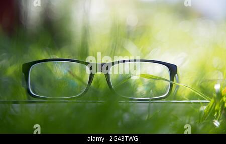 Studying outdoors: Glasses on book outdoors in the park, spring time Stock Photo
