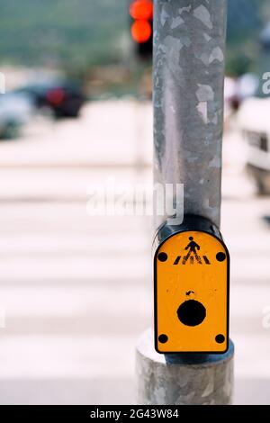 Traffic light switch button. Yellow button on traffic lights on the road with pedestrian crossing Stock Photo