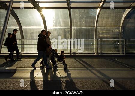 A Japanese couple pushes a pushchair through the evening light in on Hamamirai walkway in Yokohama Portside, Kanagawa, Japan. Stock Photo