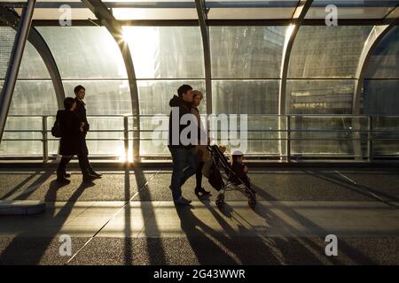 A Japanese couple pushes a pushchair through the evening light in on Hamamirai walkway in Yokohama Portside, Kanagawa, Japan. Stock Photo