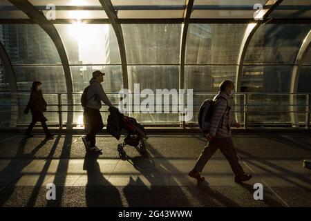 A Japanese man pushes a pushchair through the evening light in on Hamamirai walkway in Yokohama Portside, Kanagawa, Japan. Stock Photo