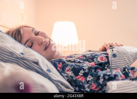 Restful sleep: Young female is sleeping in her bed, close up Stock Photo