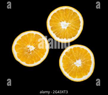 Three orange slices against black background Stock Photo
