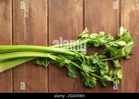 An overhead photo of fresh organic celery stalks with leaves on a dark rustic wooden background Stock Photo
