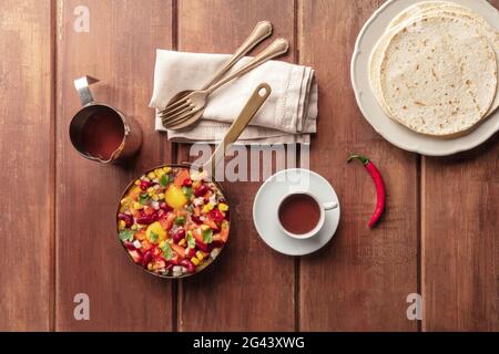 Mexican brekfast. Huevos rancheros, the fried eggs, shot from the top with the pico de gallo salad, hot chocolate, and tortillas Stock Photo