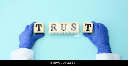 Wooden blocks with the inscription trust in the hands of the doctor on a blue background, trust in the doctor and the medical sy Stock Photo