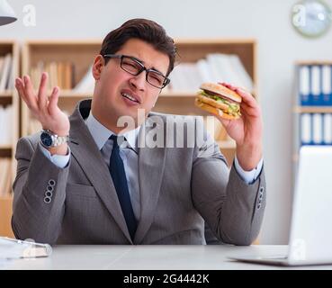 Hungry funny businessman eating junk food sandwich Stock Photo