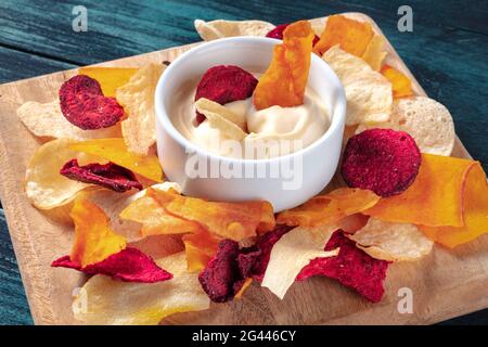 Vegetable chips with a dip on a wooden board Stock Photo