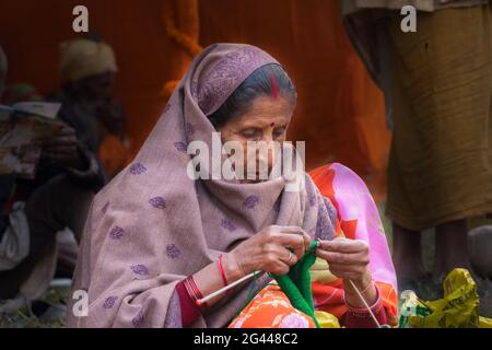 BABUGHAT, KOLKATA, WEST BENGAL / INDIA - 11TH JANUARY 2015 : Aged Indian woman knitting wool at Gangasagar transit camp. Stock Photo