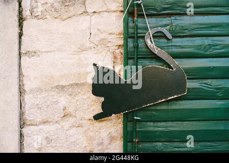 Blank signboard in the shape of a black cat hanging on an green wooden door Stock Photo