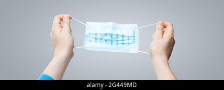 Hands in medical gloves hold medical protective mask. Stock Photo