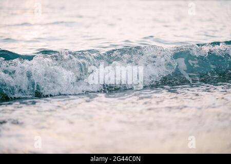 Sea waves run over one another. Close-up of a sea wave at sunset. Stock Photo