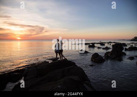 Silhouette of young couple on rocks at Ong Lang Beach at sunset, Ong Lang, Phu Quoc Island, Kien Giang, Vietnam, Asia Stock Photo