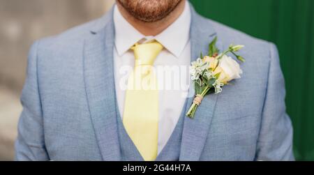 Man with stubble in a blue suit with a white shirt, yellow tie, vest and boutonniere, close-up Stock Photo