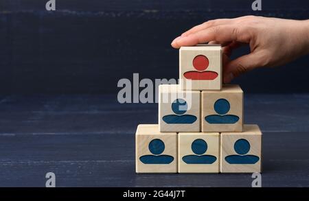 Female hand holds a wooden block on a blue background. Recruitment concept, teamwork Stock Photo
