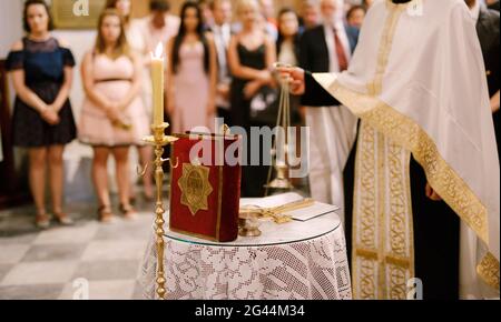 Wedding ceremony in an Orthodox church. The priest in a white cassock stand in the church at the altar, candles and bible near h Stock Photo