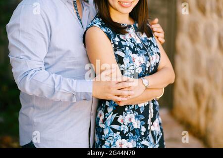 Man in a blue shirt hugs smiling woman in a colorful dress