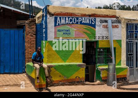 Young man sitting in front of a paint shop, Kigali, Kigali Province, Rwanda, Africa Stock Photo