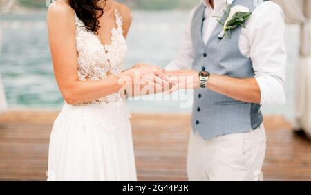 The bride puts the wedding ring on the groom's finger during the wedding ceremony by the sea Stock Photo