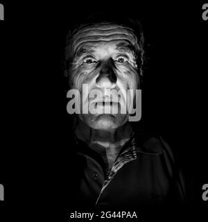 Portrait of old caucasian man. Black and white shot, low-key lighting. Isolated on black. Stock Photo