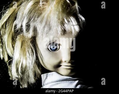 Creepy girl doll face. It seems like character of horror movie. Angry baby doll, fear of living ghost. Halloween concept. Low-ke Stock Photo