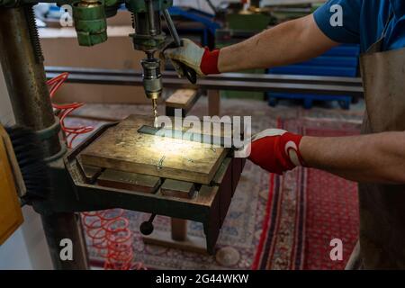 A metal worker drilling holes in metal with a bench drill Stock Photo