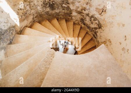 Newlyweds are seen through the spiral staircase of the ancient castle. View from above Stock Photo