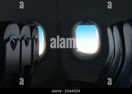 Beautiful low key photograph of cabin interior of passenger airplane with amazing blue tint of sky from window. It is flying with vacant and empty row Stock Photo