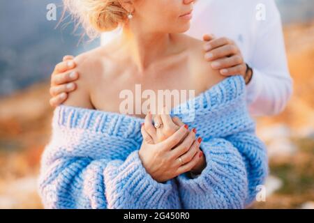 Man hugs a woman in a blue sweater by the shoulders. Close up Stock Photo