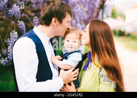Mother and father kissing their red-haired toddler Stock Photo
