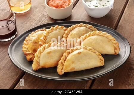 A closeup of Argentinian empanadas with sauces and wine Stock Photo