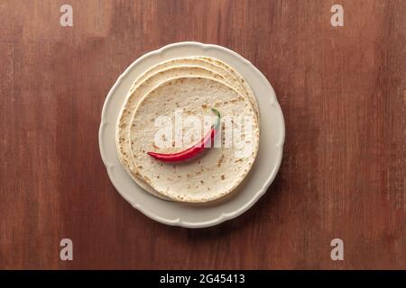 A red chili pepper, shot from above on a pile of tortillas, Mexican flatbreads Stock Photo