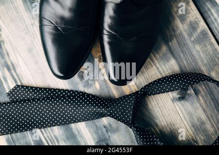 Socks of black leather mens shoes with a polka dot tie on a wooden texture close-up. Stock Photo