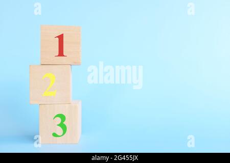 Colorful 123 numbers on wooden blocks in blue background with copy space. Start of child or kid learning counting concept. Stock Photo