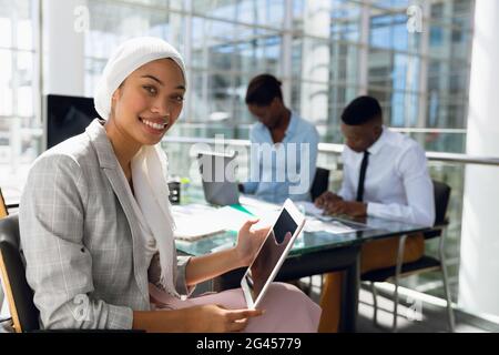 Businesswoman in hijab using digital tablet at desk in office Stock Photo